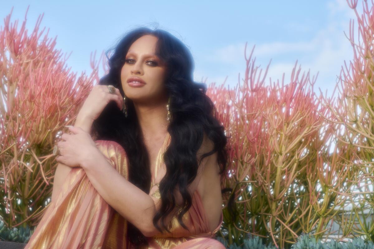 Sasha Colby wears a gown and sits in a rooftop garden.