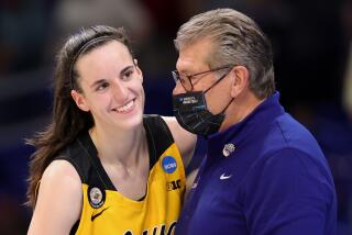 UConn coach Geno Auriemma wears a mask while speaking with Iowa's Caitlin Clark