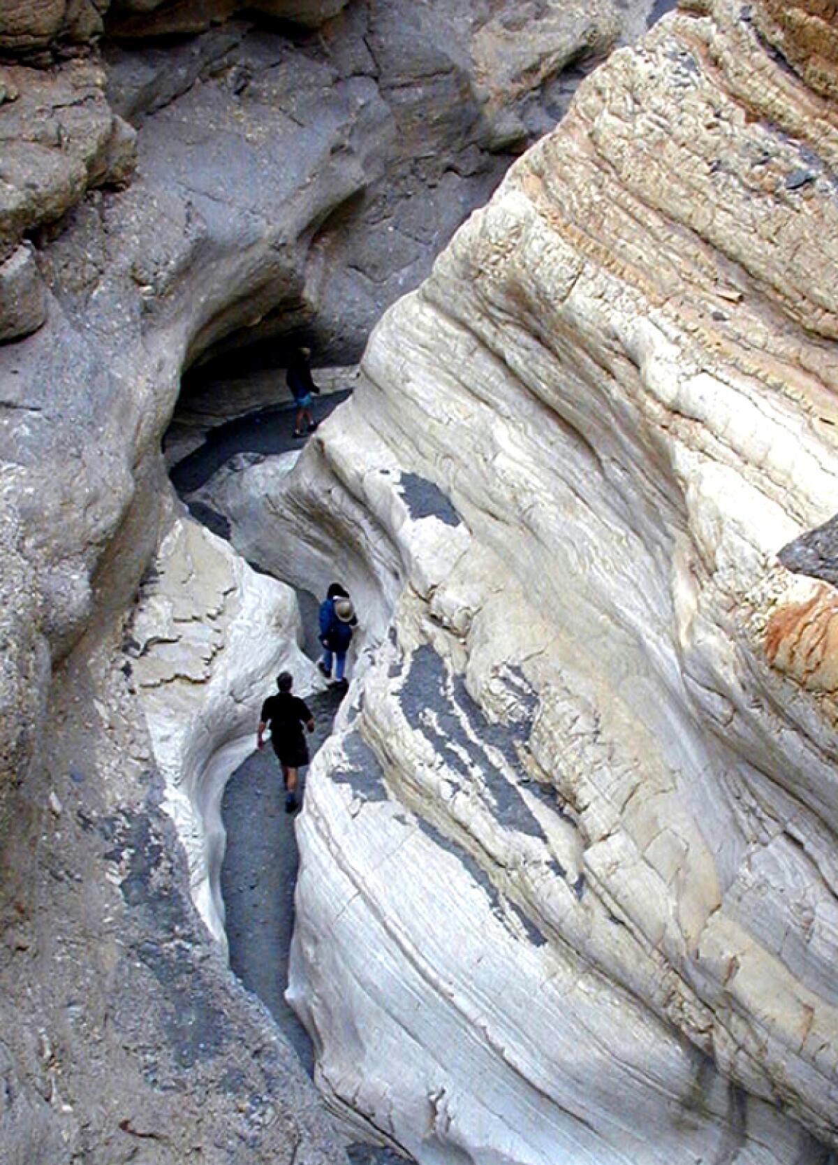 People walk in a narrow canyon.