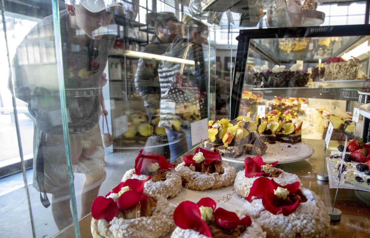 Customers looking the display window with a tray of Crostata Caramelized Apple in the foreground at Extraordinary Desserts in San Diego.
