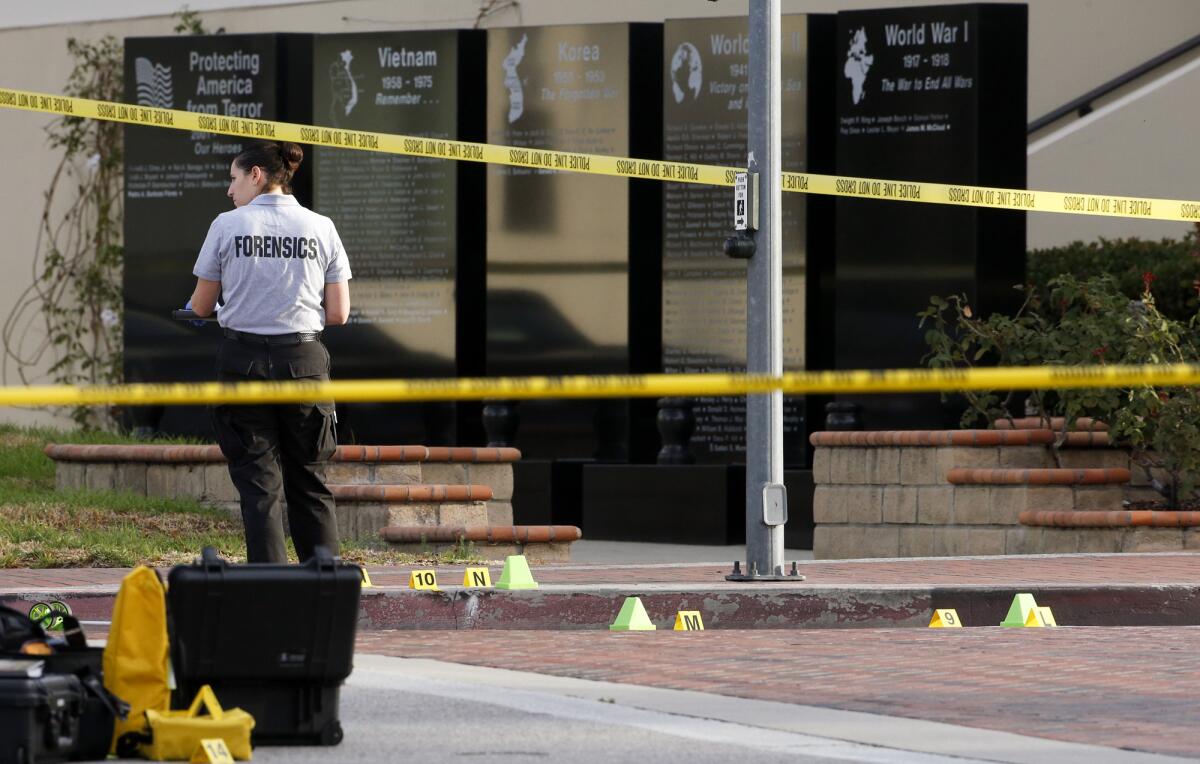A Glendale Police investigator processes the evidence around a crime scene where one man was found dead in front of the Glendale courthouse and another man suffered serious stab wounds early Monday morning.
