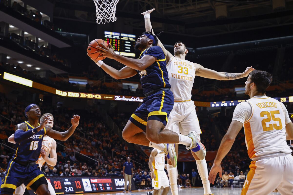 UNC-Greensboro forward Jalen White (14) shoots past Tennessee forward Uros Plavsic (33) during an NCAA college basketball game Saturday, Dec. 11, 2021, in Knoxville, Tenn. (AP Photo/Wade Payne)