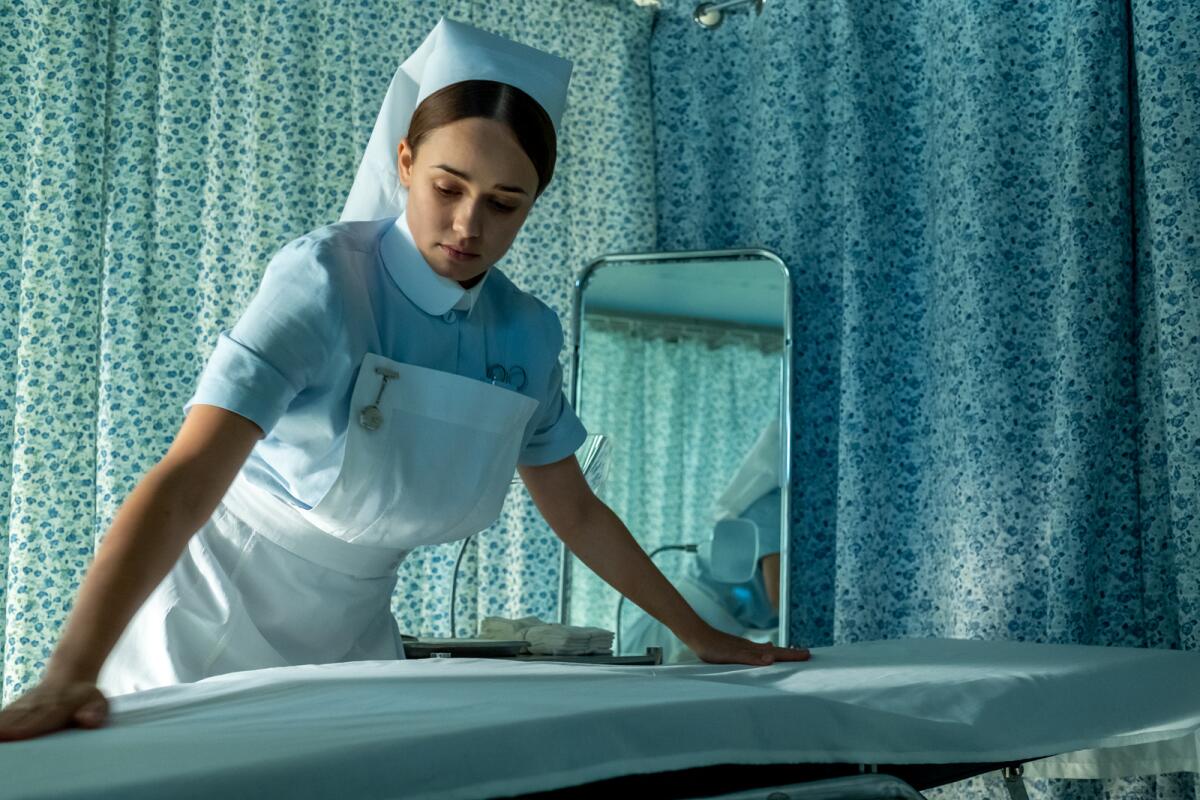 A nurse smooths a sheet.