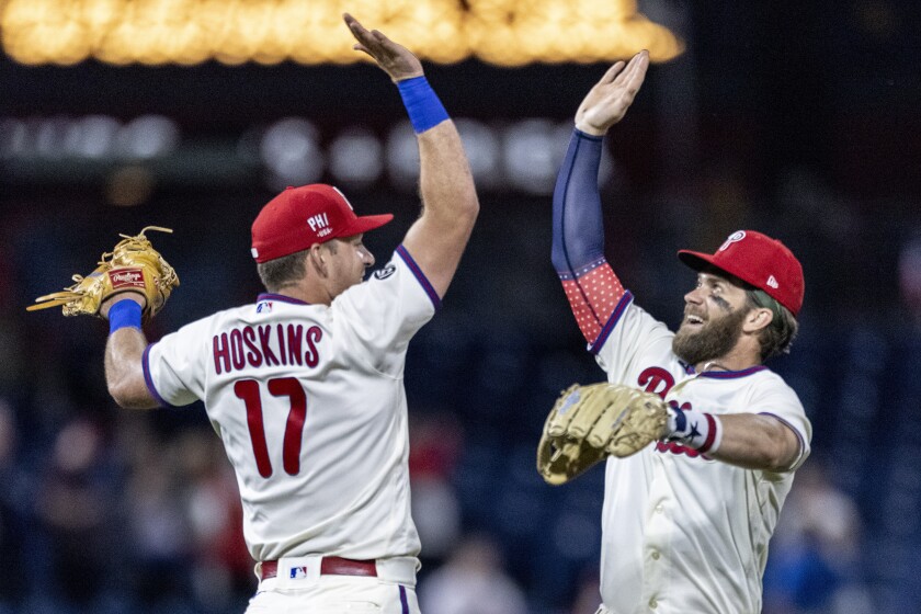 Philadelphia Phillies first baseman Rhys Hoskins (17) and right fielder Bryce Harper, right, celebrate after the Phillies defeated the San Diego Padres 4-2 in a baseball game, Saturday, July 3, 2021, in Philadelphia. (AP Photo/Laurence Kesterson)