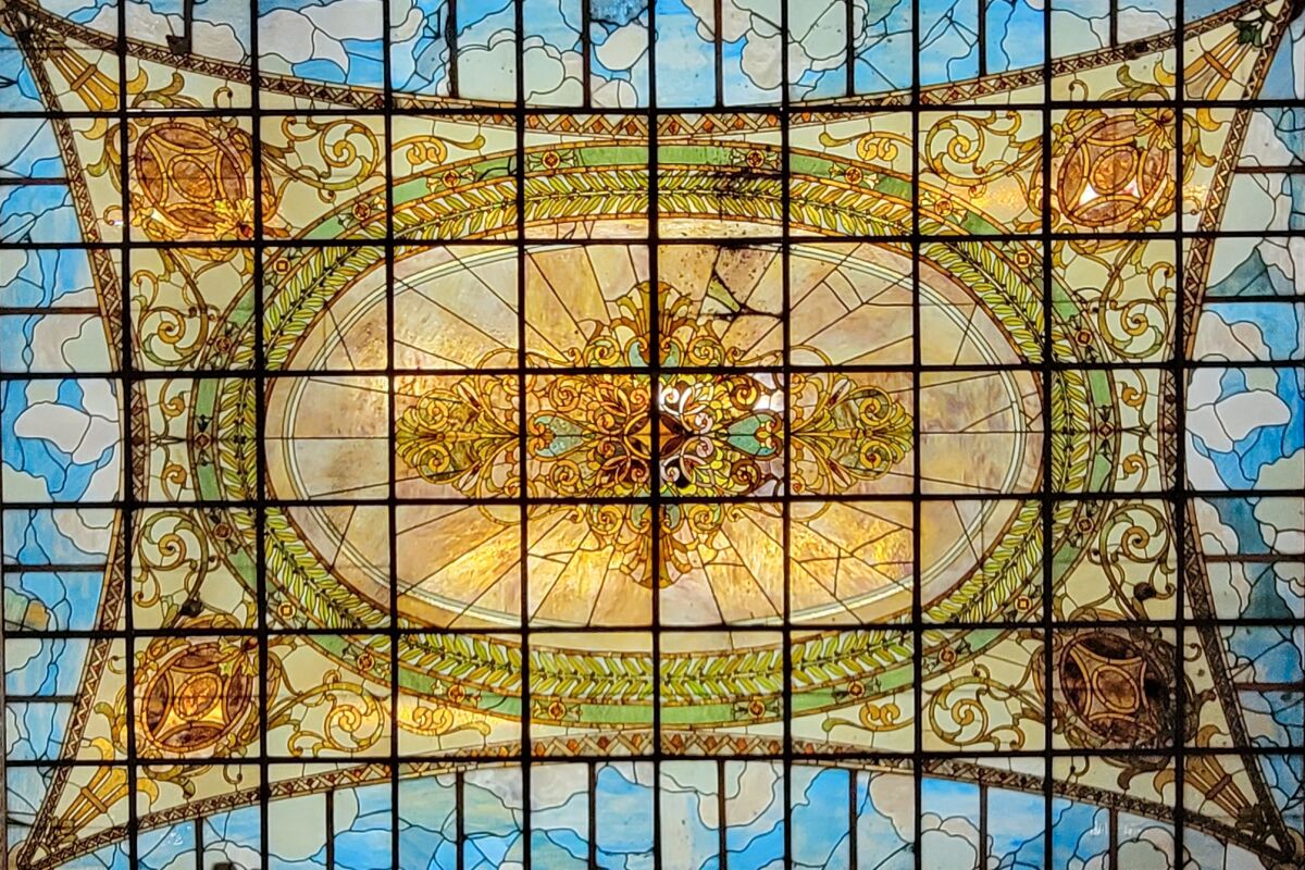 A skylight made of stained glass that looks like a glowing tapestry against a blue-sky background.