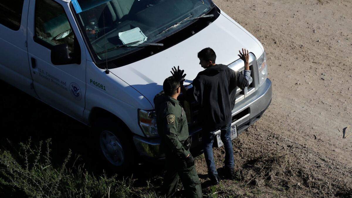 In this Wednesday, Nov. 16, 2016, photo, a U.S. Customs and Border Patrol agent works with a suspected immigrant entering the country illegally along the Rio Grande in Hidalgo, Texas.