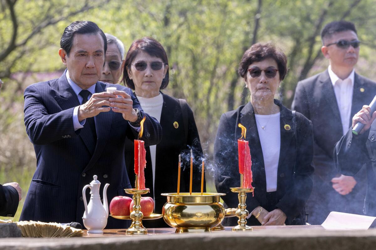 Former Taiwanese President Ma Ying-jeou, left, pays respects at his grandfather's tomb.