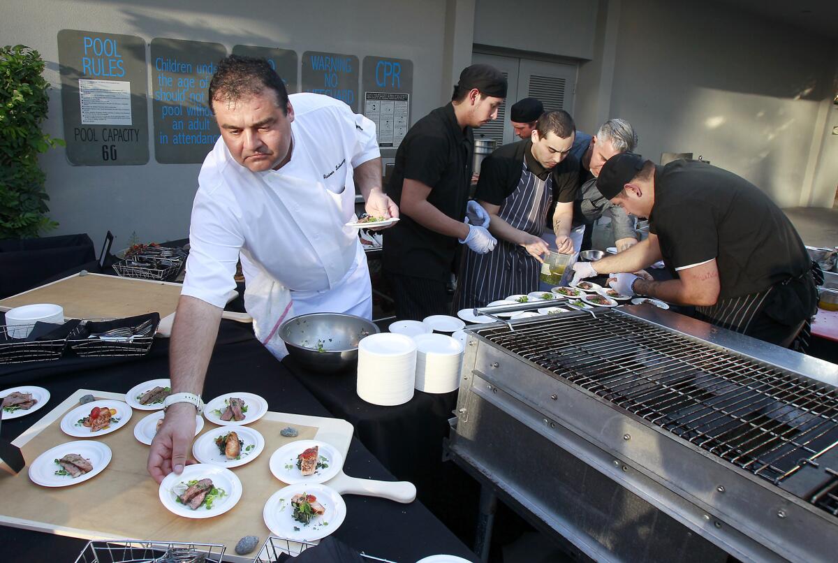 Chef Rainer Schwarz, left, and his crew work diligently to serve grilled tavern rib-eye steaks and bay salmon for guests during grand opening of Fireside in the Crowne Plaza hotel in Costa Mesa on Thursday.