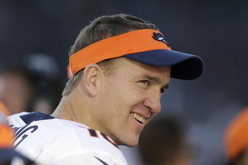 FILE - Denver Broncos quarterback Peyton Manning smiles while standing.