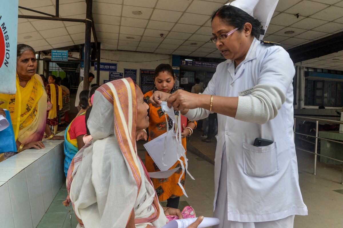 A nurse places a protective mask on a patient at a government hospital in Siliguri, India.