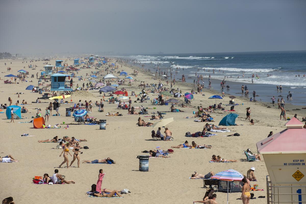 Beachgoers flock to the sand on the south side of the Huntington Beach Pier on Tuesday.