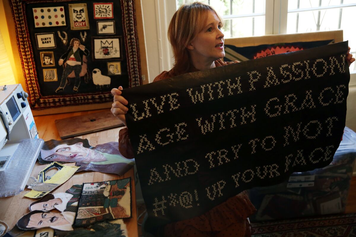 Lisa Borgnes-Giramonti holds up one of her embroidery pieces while in her home studio in Hollywood Heights
