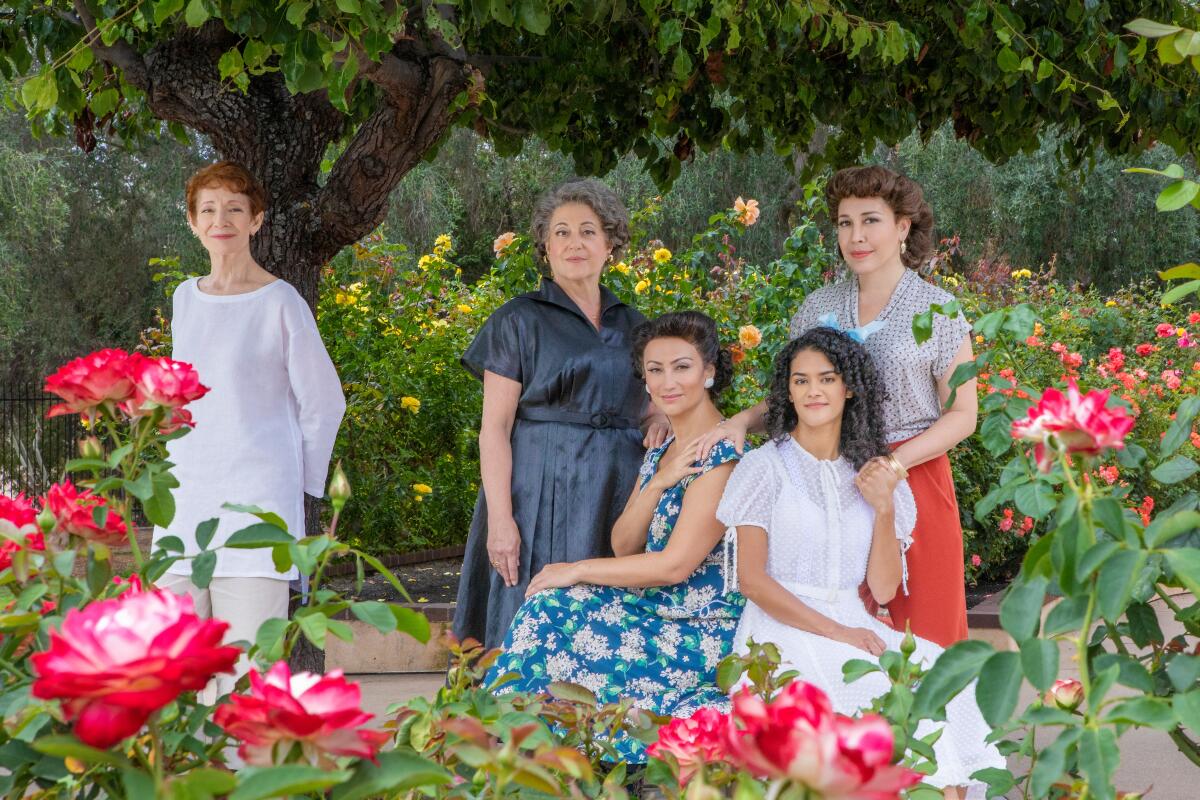 "The Gardens of Anuncia" cast is photographed in a garden filled with rose plants