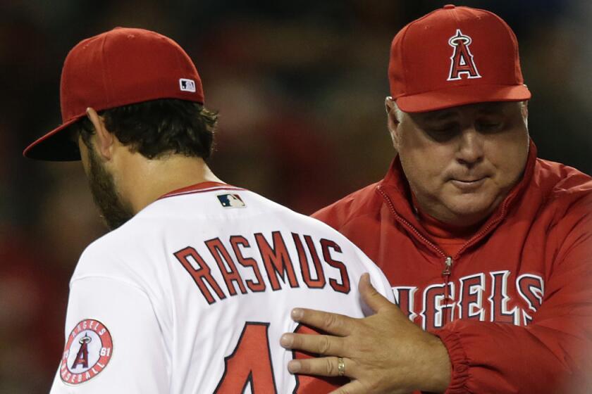 Angels manager Mike Scioscia pats pitcher Cory Rasmus on the back as he removes him from the game in the seventh inning against the Rangers on April 8.