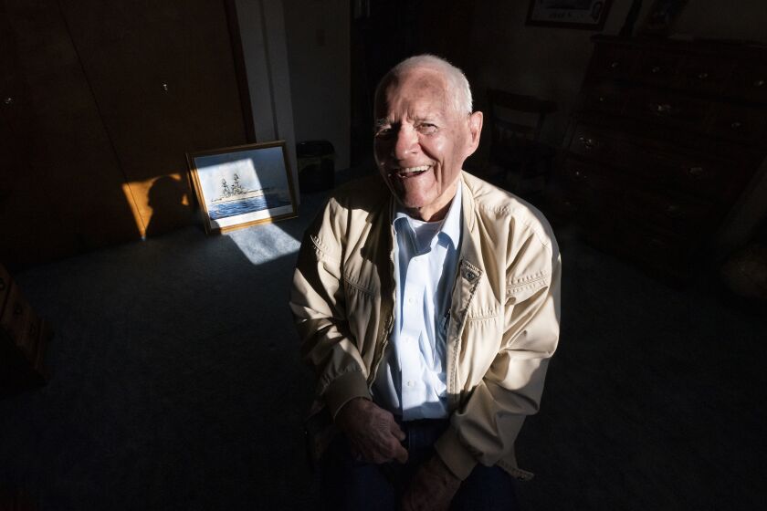 Pearl Harbor survivor and World War II Navy veteran David Russell, 101, poses for a photo along with a painting of the USS Oklahoma at his home on Monday, Nov. 22, 2021, in Albany, Ore. (AP Photo/Nathan Howard)