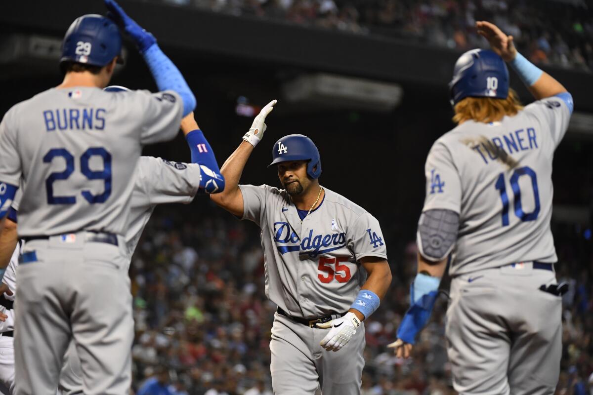 Albert Pujols celebrates his home run with Andy Burns and Justin Turner. 