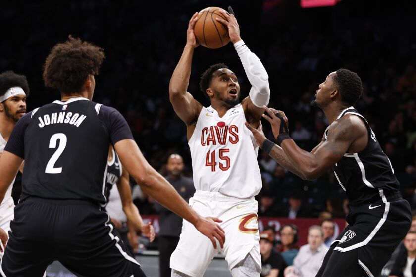 Cleveland Cavaliers guard Donovan Mitchell (45) drives to the basket against Brooklyn Nets forwards Dorian Finney-Smith and Cameron Johnson (2) during the first half of an NBA basketball game, Tuesday, March 21, 2023, in New York. (AP Photo/Noah K. Murray)