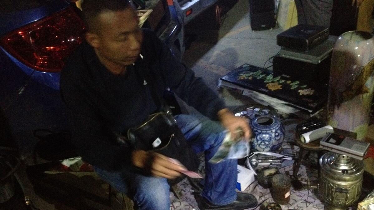 A seller at the ghost market in Beijing gives change to a customer. Aside from what was laid out, he also had merchandise in the trunk of his car.