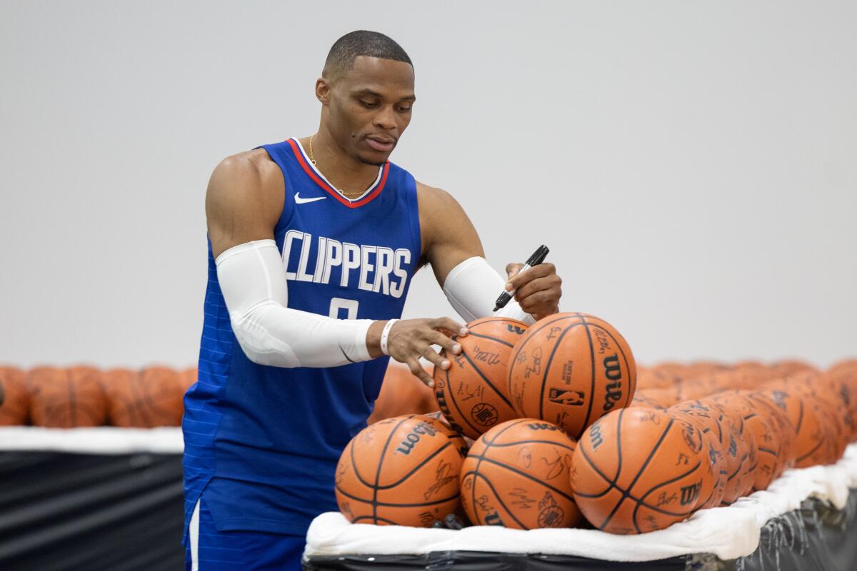 Russell Westbrook autographs a table full of basketballs