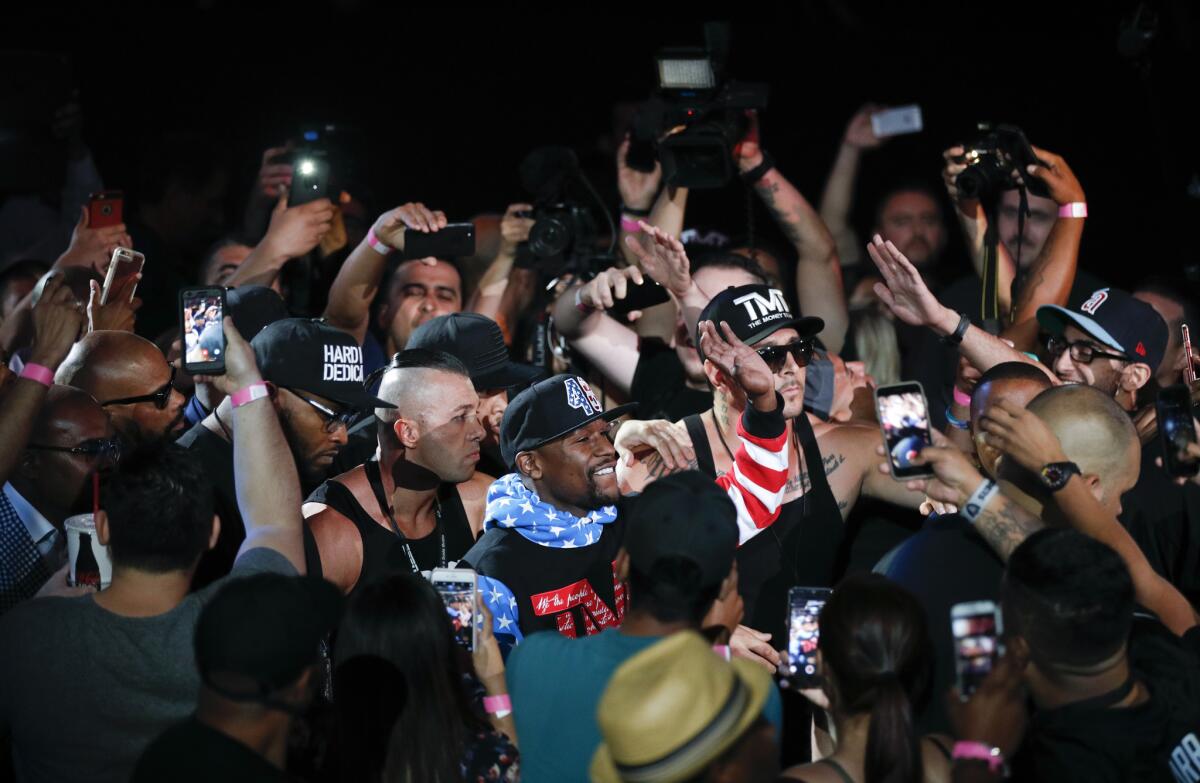 El boxeador Floyd Mayweather Jr. se abre paso entre los fanáticos para ofrecer una conferencia de prensa en el Staples Center de Los Ángeles, el martes.