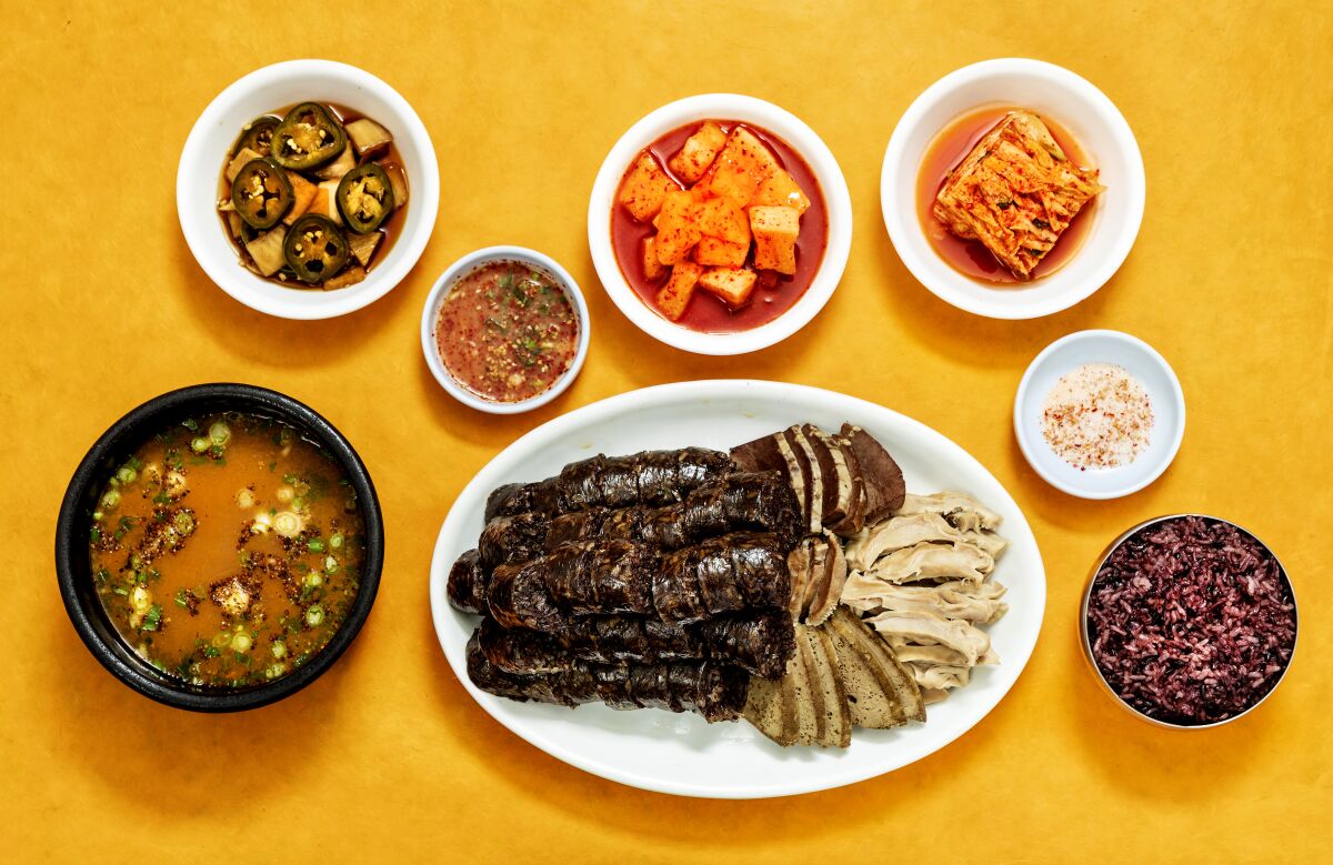 A large plate of soondae -- liver, tongue, heart and stomach -- accompanied by dipping sauces, soup and rice.