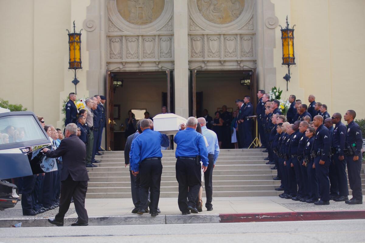 Pallbearers carry a casket into a church as police officers stand on the steps