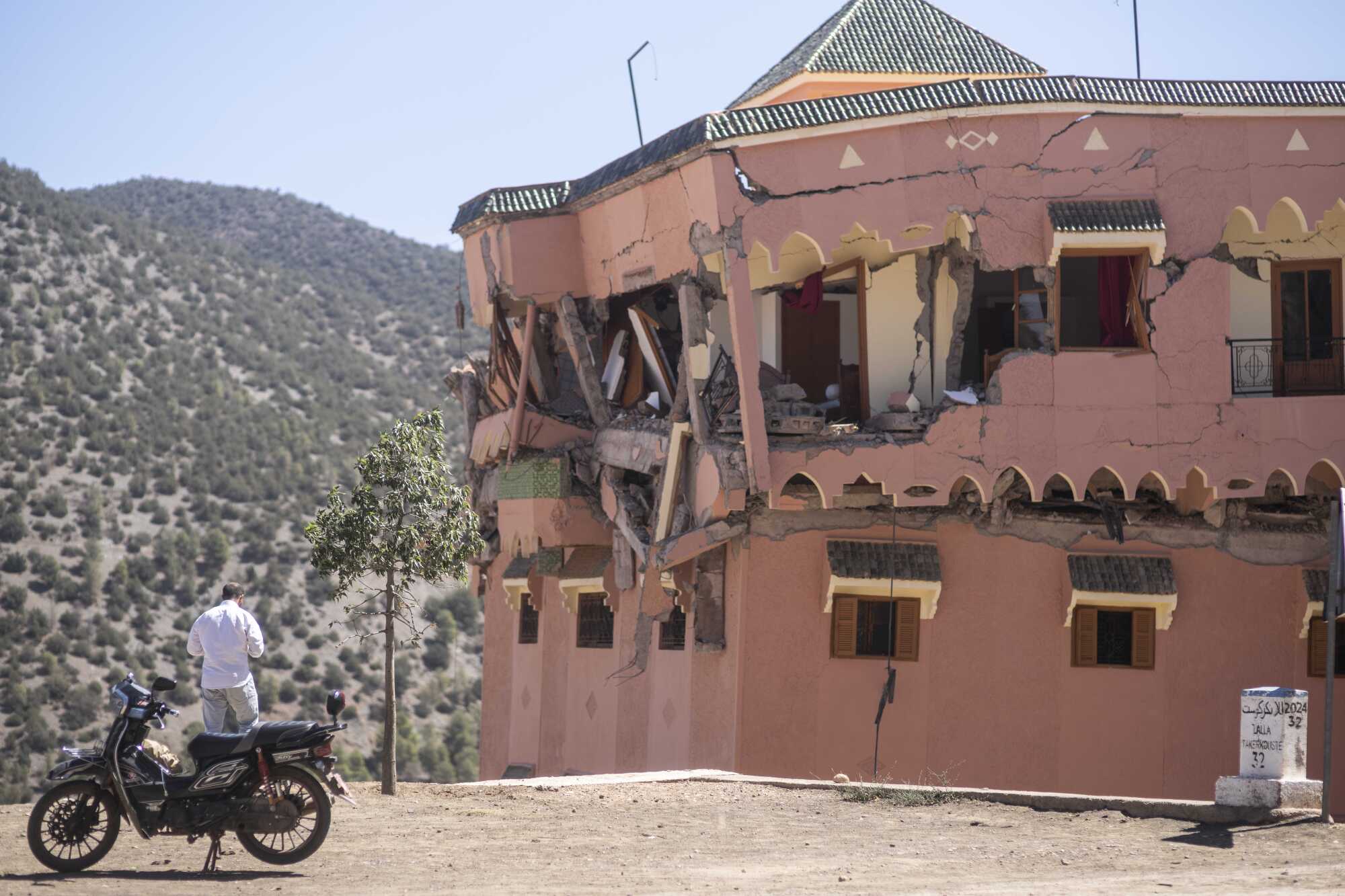 A man stands next to a damaged hotel after the earthquake in Moulay Brahim village