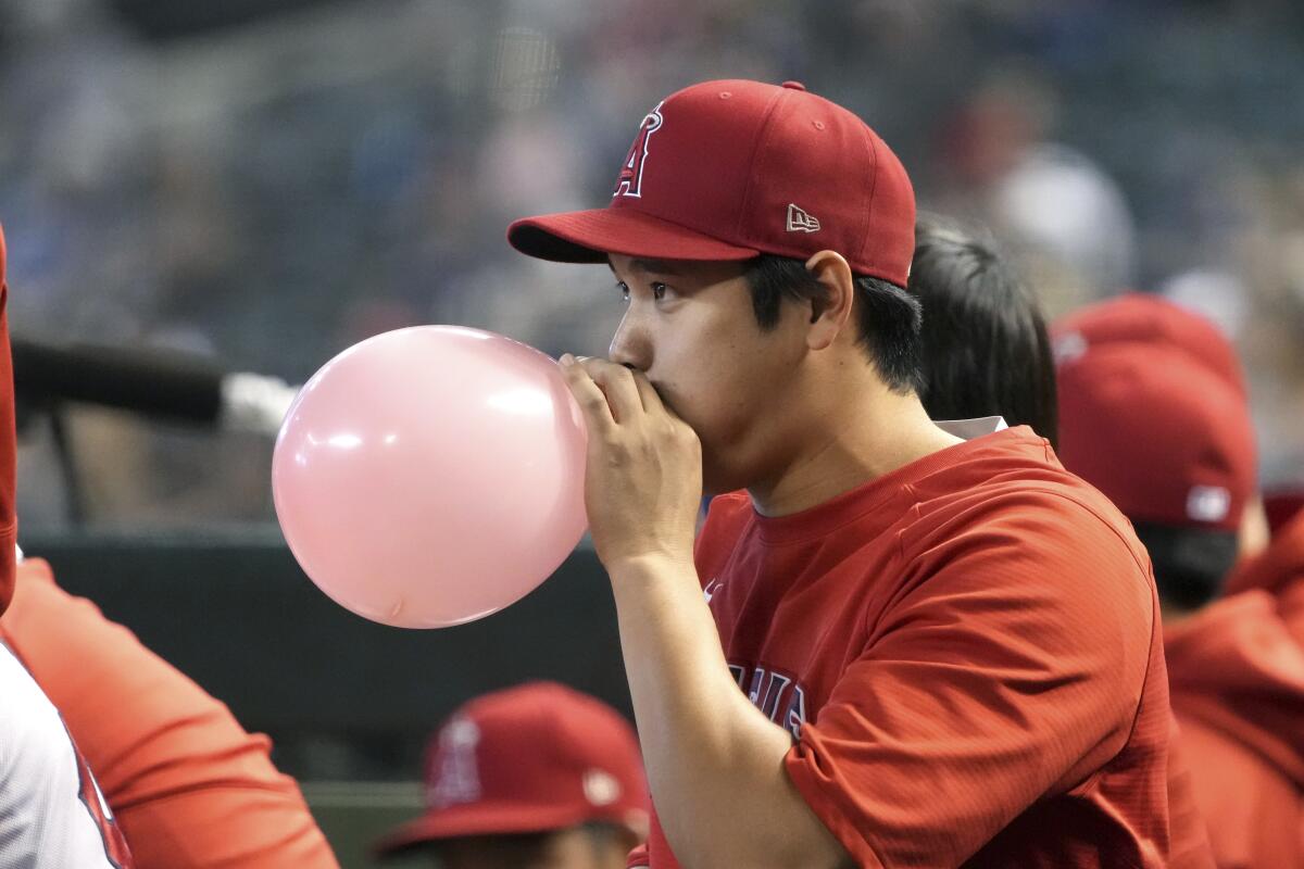 Angels star Shohei Ohtani blows up a balloon in the dugout during the ninth inning of Sunday's win over the Diamondbacks.