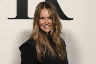 Elle Macpherson smiles in a high-neck black blazer with her hair down 