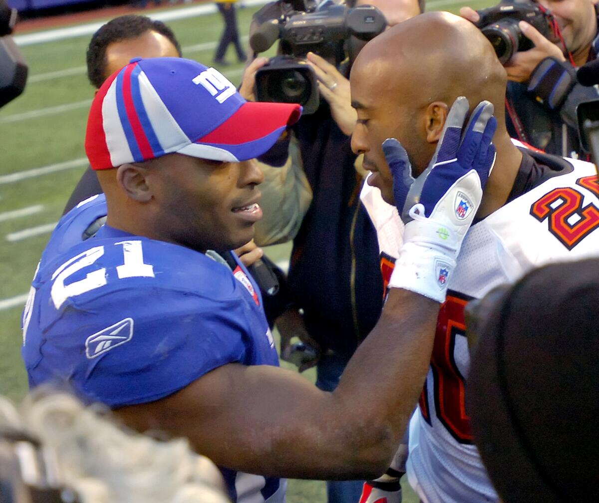 Giants back Tiki Barber, left, talks with twin brother,  Buccaneers cornerback Ronde Barber, after their game in 2006.