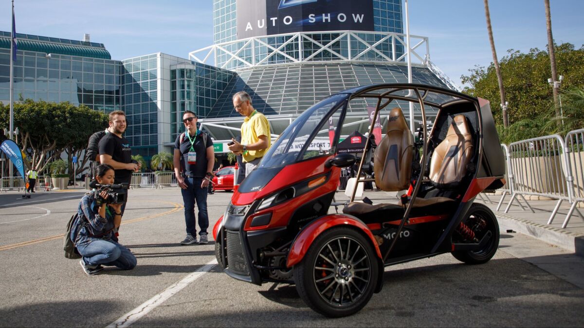 Visitors check out an Arcimoto SRK three-wheeled electric vehicle at AutoMobilityLA, a day before the LA Auto Show opened to the public.