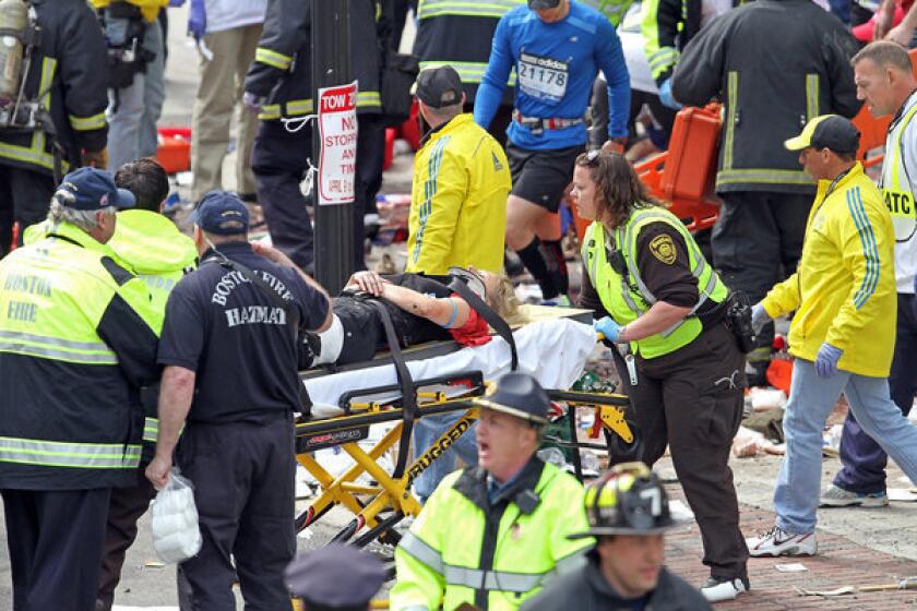 Rescue personnel aid injured people near the finish line of the 2013 Boston Marathon following explosions in Boston, Monday, April 15, 2013. Two explosions shattered the euphoria of the Boston Marathon finish line on Monday, sending authorities out on the course to carry off the injured while the stragglers were rerouted away from the smoking site of the blasts. (AP Photo/The Boston Herald, Stuart Cahill) ** Usable by LA and DC Only **