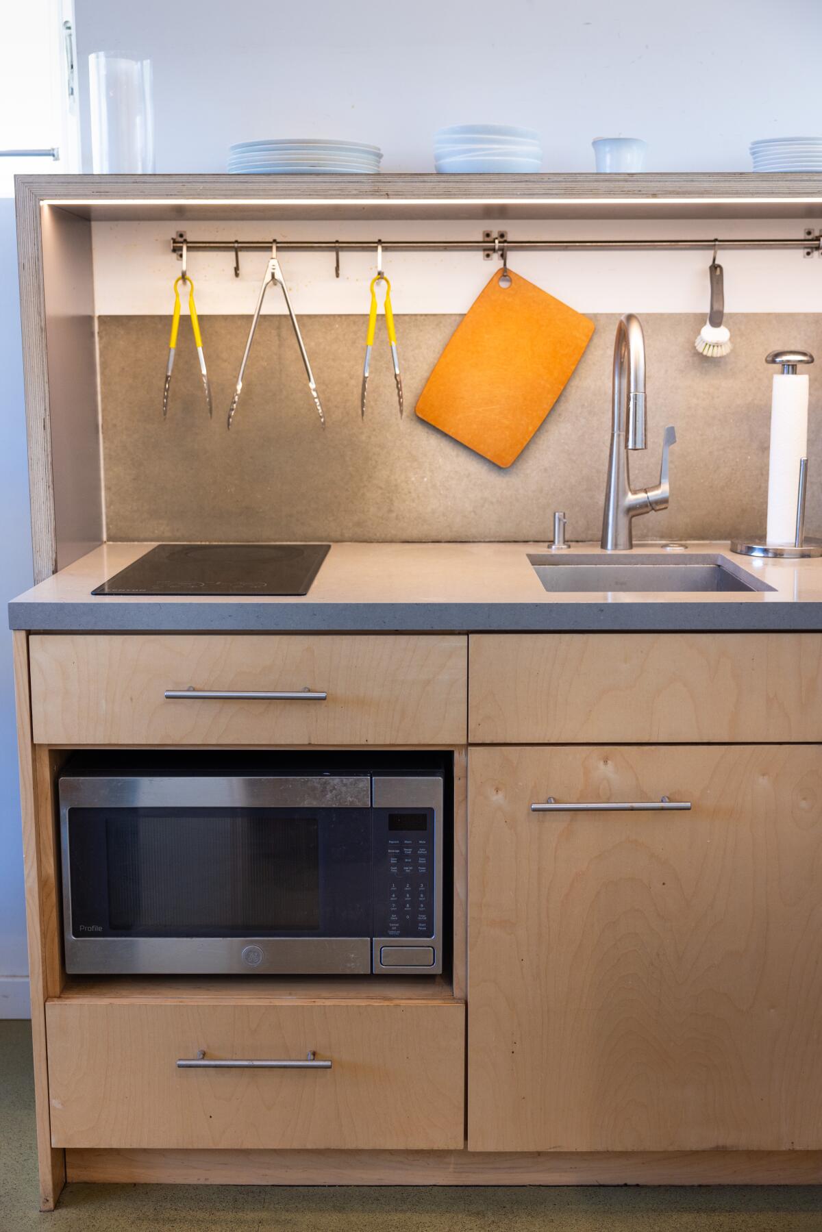 An induction stove sits above the microwave and near the small sink in the kitchen.