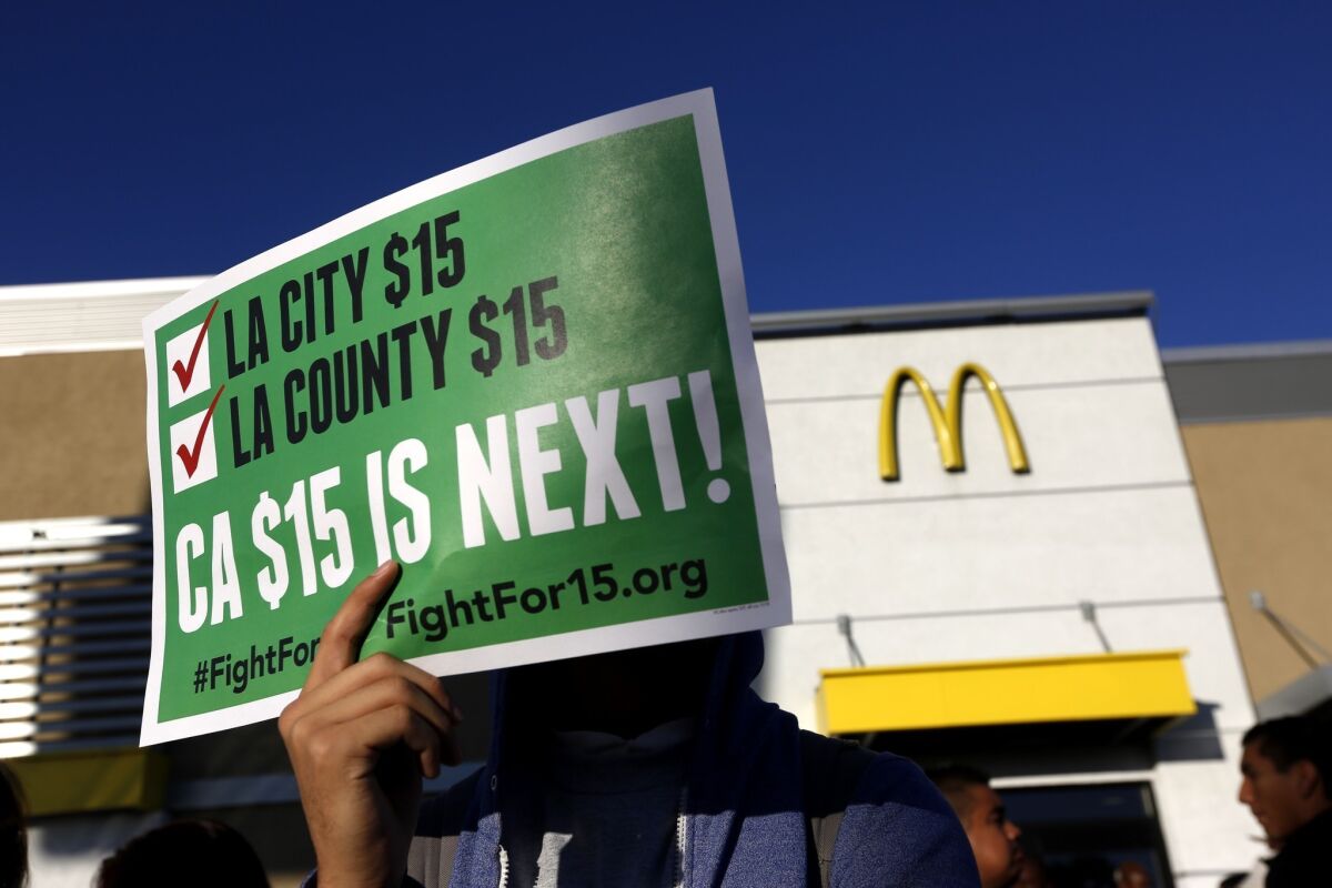 A person holds up a sign pushing for a $15 minimum wage in California.