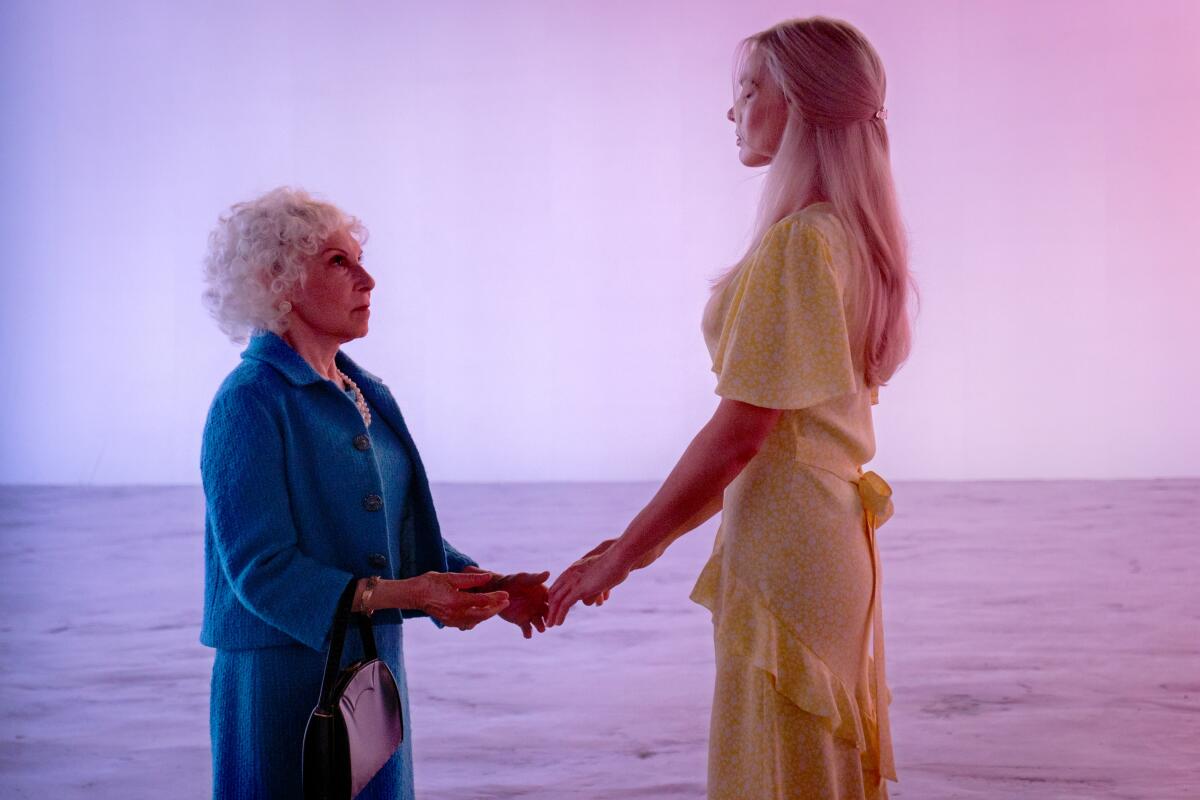 A movie still in which an older woman addresses a younger one as they stand on a beach 