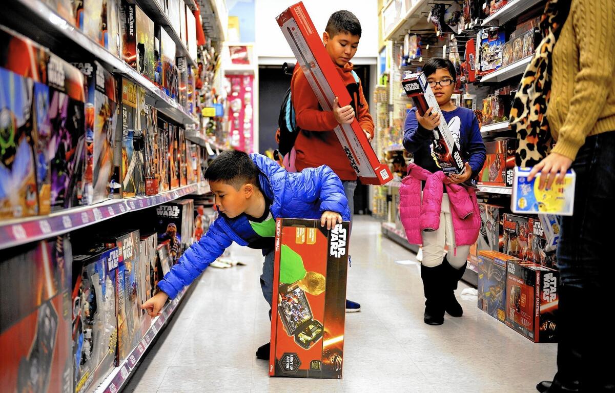 Inaki, 7, left; Inigo, 13; and Bianca Casido, 9, shop for "Star Wars" toys at a Toys R Us in Los Angeles with their mother, Kristine, this week.