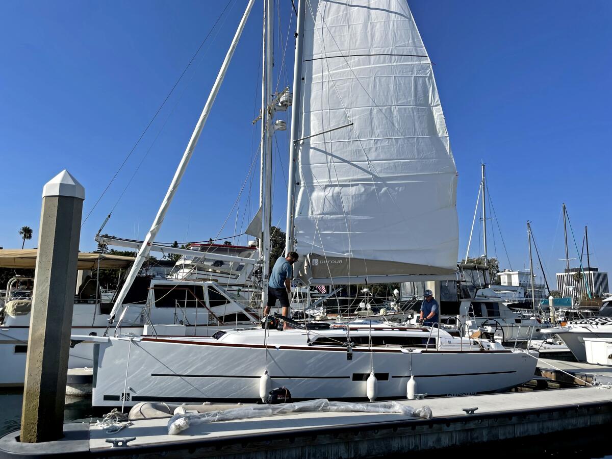 A man works on the deck of a sailboat. 