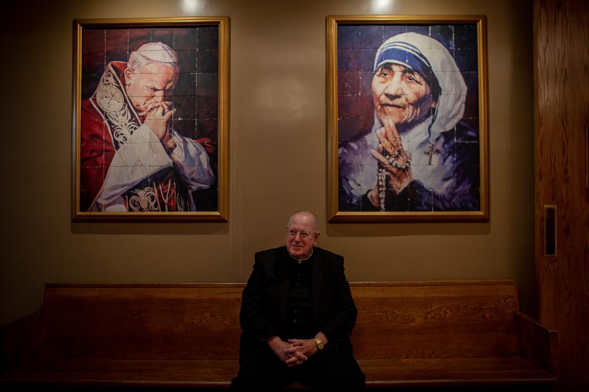 Msgr. John Moretta of Resurrection Catholic Church sits between portraits of Pope John Paul II and Mother Teresa.