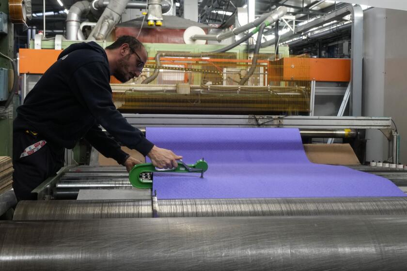 Un trabajador revisa la superficie final para la pista de atletismo para los Juegos Olímpicos de París en la fábrica de Mondo en Alba, al norte de Italia el miércoles 13 de marzo del 2024. (AP Foto/Luca Bruno)