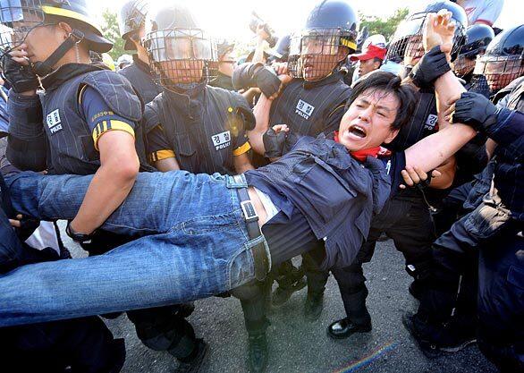 South Korean riot police detain a protester during a rally in support of striking workers near the Ssangyong Motors plant in Pyeongtaek, south of Seoul.