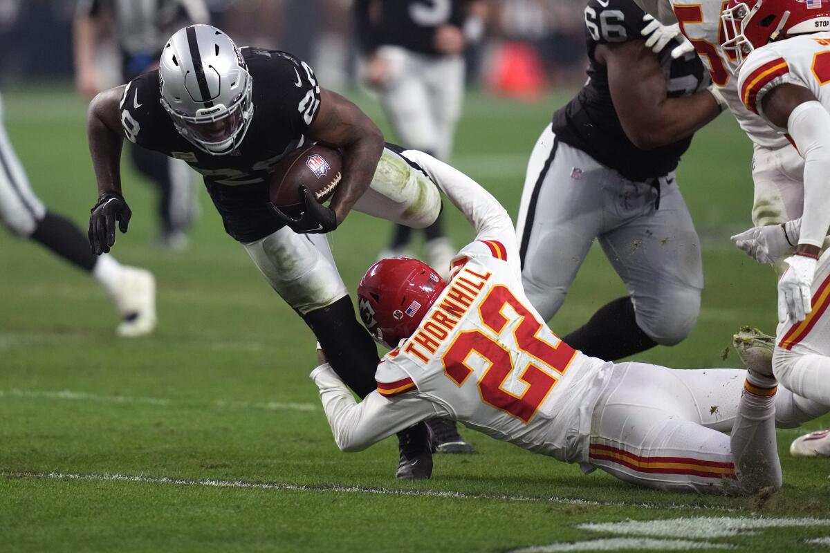 Raiders running back Josh Jacobs is brought down by Chiefs safety Juan Thornhill on Jan. 7, 2023.