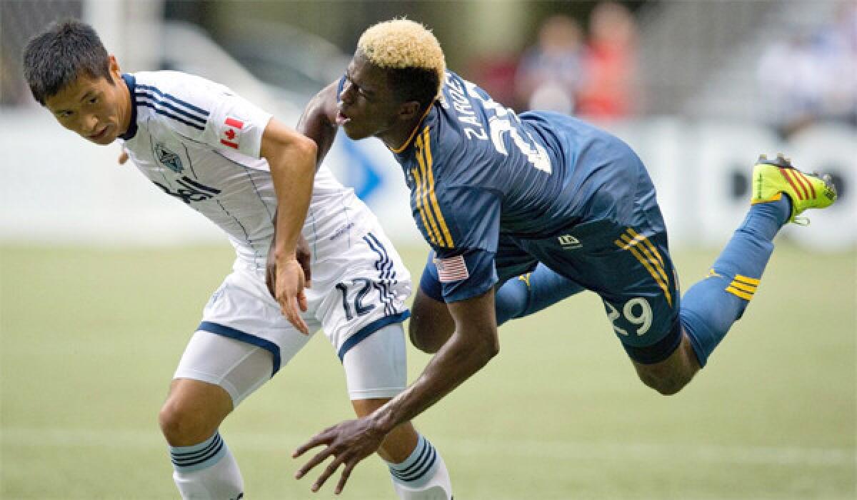 Forward Gyasi Zardes is sent flying after a collision with defender Lee Young-Pyo during the first half of the Galaxy's win over the Vancouver Whitecaps FC, 1-0, on Aug. 24, 2013.