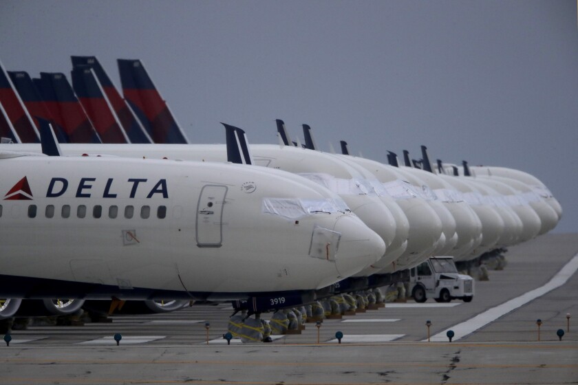 FILE - In this May 14, 2020 file photo, several dozen mothballed Delta Air Lines jets are parked on a closed runway at Kansas City International Airport in Kansas City, Mo. Delta Air Lines says it lost $1.2 billion in the first quarter, but the airline thinks it can by profitable by late summer unless there's a resurgence of COVID-19. Delta reported the results on Thursday, April 15, 2021. (AP Photo/Charlie Riedel, File)