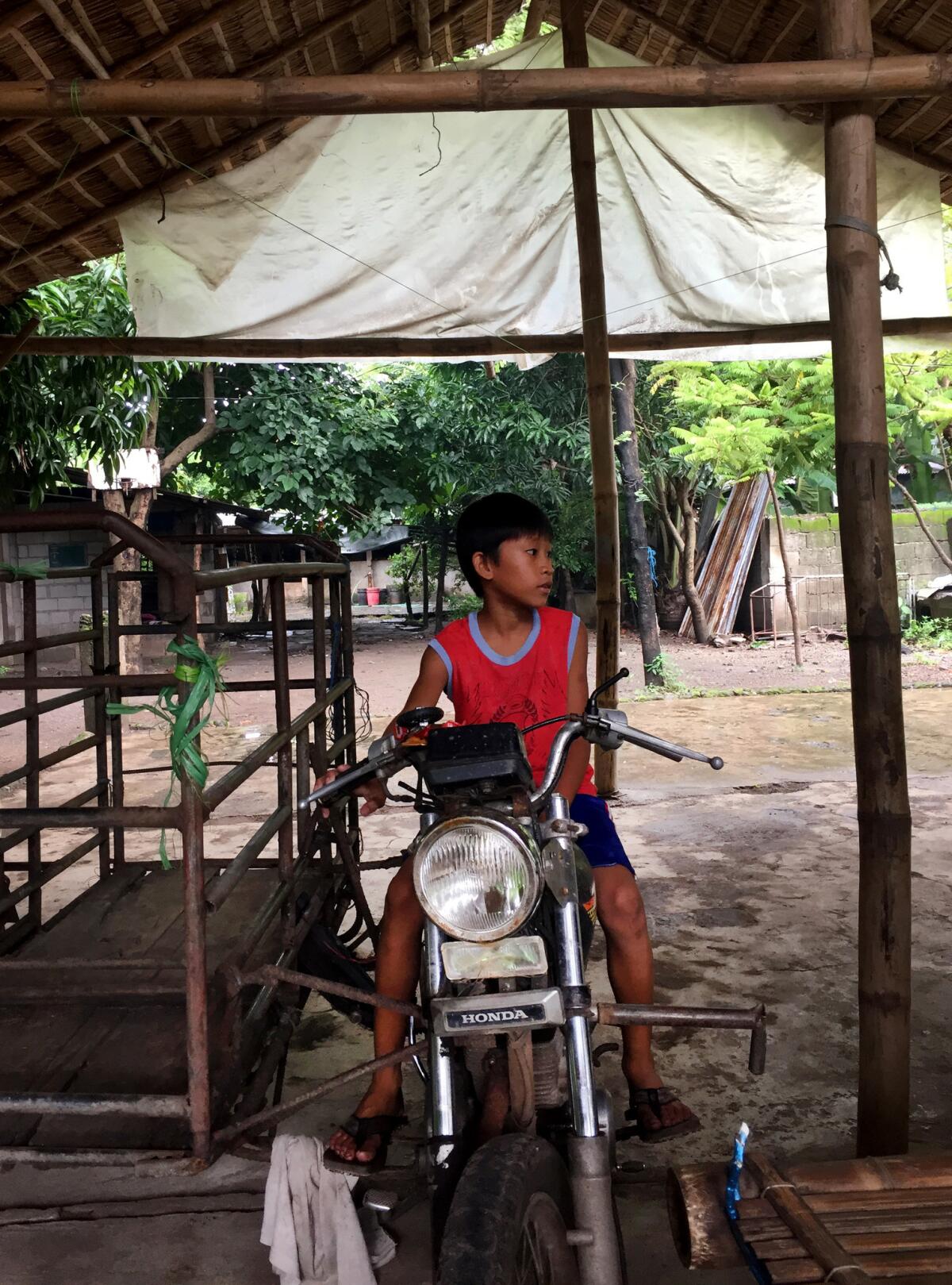 Deceased environmental activist Gloria Capitan's grandson Jerson, 8, plays on a motorbike at the family's home.