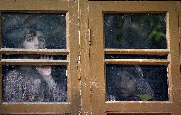 Kashmiri children look out from a window of their house during a gun battle between Indian soldiers and suspected militants at Ladhoo, about 16 miles south of Srinagar, India. An Indian soldier was injured in the gun battle, which began Tuesday morning in the forested area of Ladhoo, in Khrew district, a news agency cited police as saying.