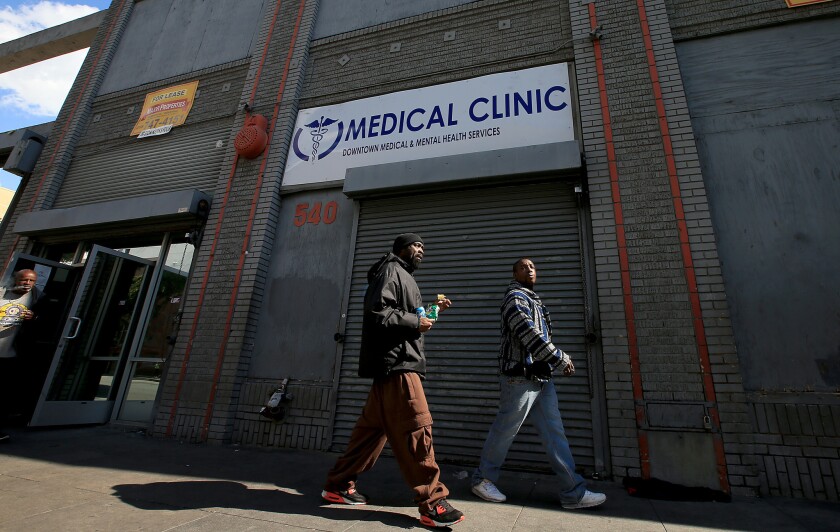 Men walk past the Downtown Medical and Mental Health Services center, where homeless people gather. The center is trying to expand its drug treatment programs, but battling bureaucratic hurdles.