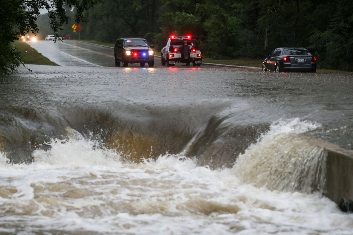 A police officer directs traffic away after a car is stranded in flash flooding on Friday in The Woodlands, Texas.