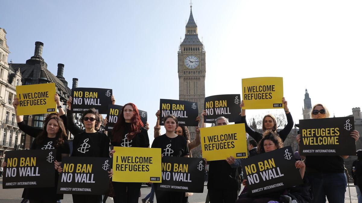 Amnesty International activists protest against President Trump's travel ban in Parliament Square on March 16, 2017 in London.