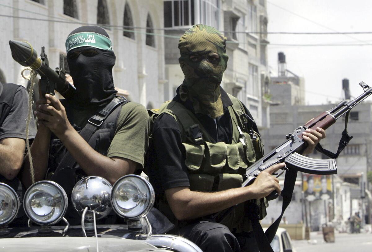 ARCHIVO - Combatientes palestinos de Hamas marchan en una camioneta con sus armas 