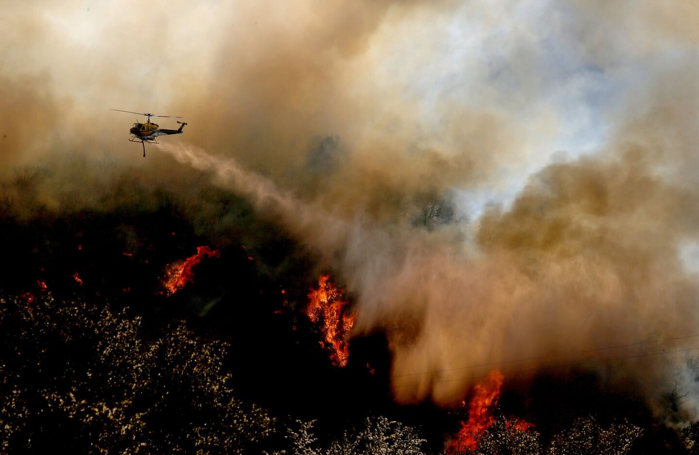 A firefighting helicopter makes a water drop on a flare-up of the Blue Cut fire along Interstate 15 in the Cajon Pass on Thursday.